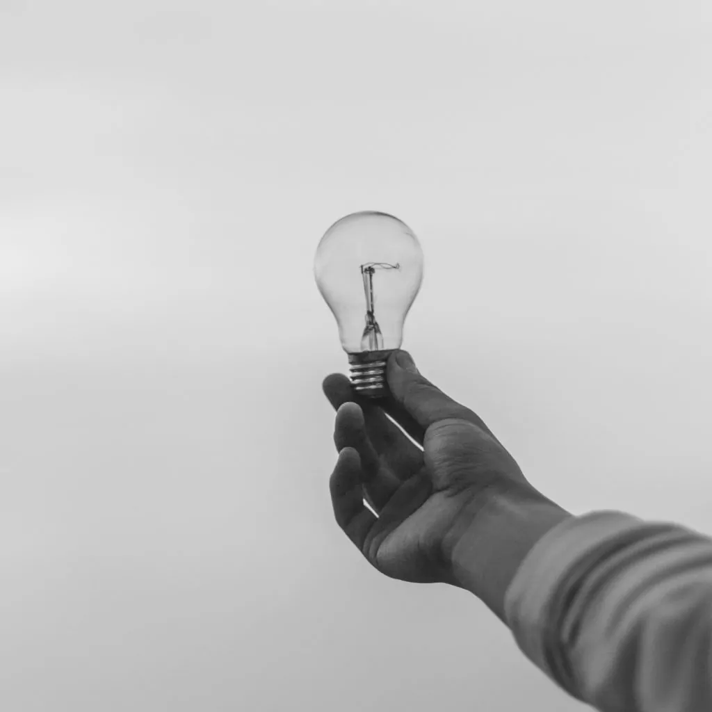 a hand holding a light bulb to the sky