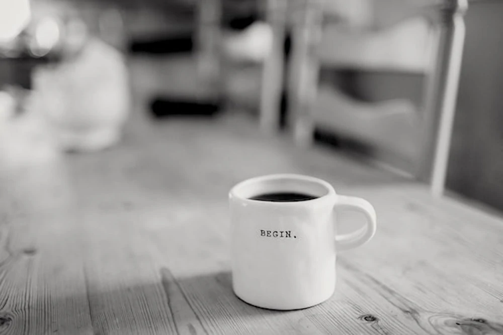 Coffee cup on a table with begin written on it